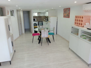 grand séjour, rangement vaisselle à droite, table ronde avec 4 chaises + 2 à la demande, rangement à gauche de la chambre du milieu