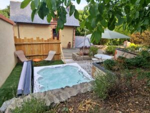 Le Spa privatif et la terrasse avec une vue de la maison du Gardien depuis l'extérieur - rdc côté haut